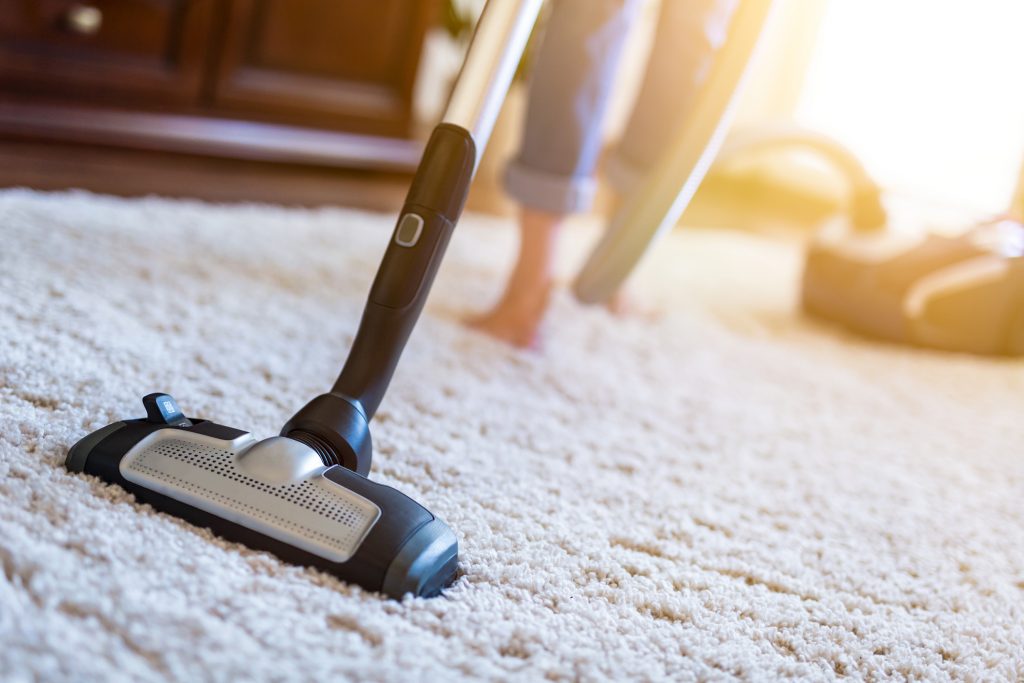 woman vacuuming floor preparing for carpet cleaning