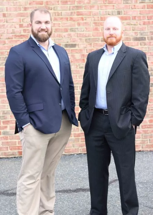 Two men in business attire standing outside brick building, representing a local power washing company team.